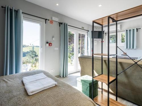 a bedroom with a bed and a bathroom with windows at Villas Pomar do Moinho in Usseira