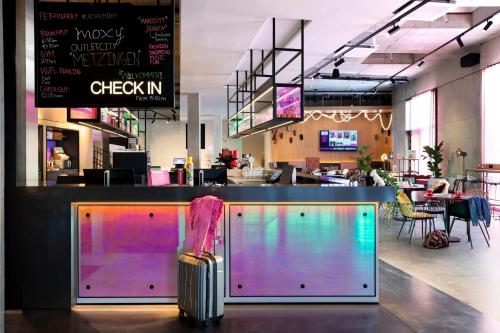 a restaurant with a colorful bar with a luggage at Moxy Outletcity Metzingen in Metzingen