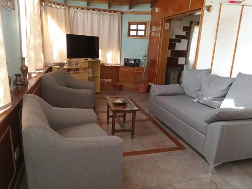 sala de estar con 2 sofás y TV en Departamentos Ahnen en Ushuaia
