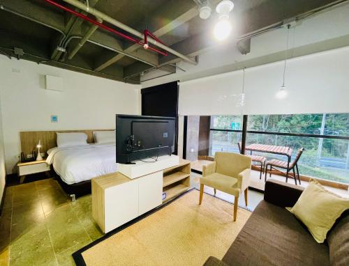 1 dormitorio con 1 cama, TV y sofá en Suite hotelera llanogrande, en Rionegro