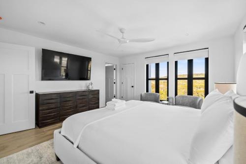 a white bedroom with a large bed and a tv at Las Luces in Spicewood