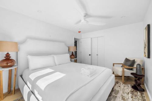 a white bedroom with a white bed and a chair at Las Luces in Spicewood