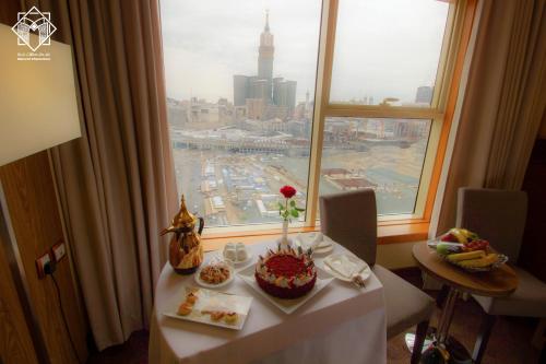 a table with a cake on it in front of a window at Manarat Gaza Hotel - Al Haram Tower in Makkah