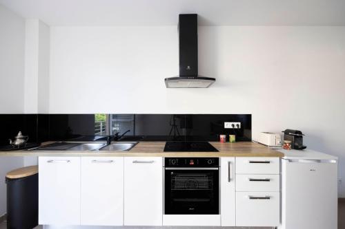 a kitchen with white cabinets and a black oven at Perle Noire - Séjours d'affaires - DestinationGuyane - Route des plages in Rémire-Camp