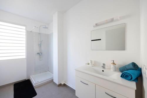 a white bathroom with a sink and a mirror at Perle Noire - Séjours d'affaires - DestinationGuyane - Route des plages in Rémire-Camp