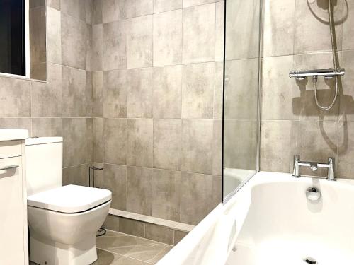 a bathroom with a toilet and a bath tub at Sandringham House Serviced Rooms in Hartlepool