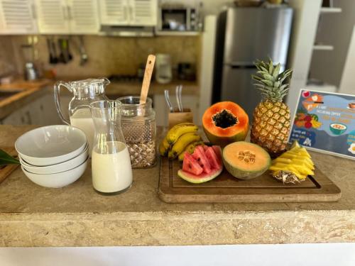 a counter with a cutting board with fruit and milk at Maloca by Villa Clarissa8 in Las Terrenas