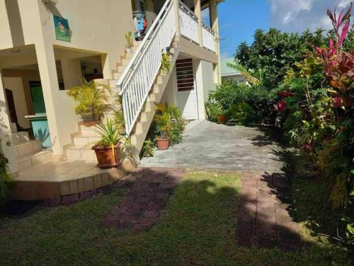 a house with stairs and potted plants in a yard at La Gîte Le Sucrier au Lamentin -10 min du CHUM in Le Lamentin