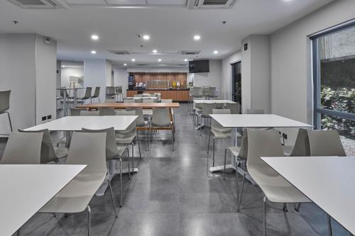 a dining room with white tables and chairs at City Express by Marriott Queretaro Autopista in Querétaro