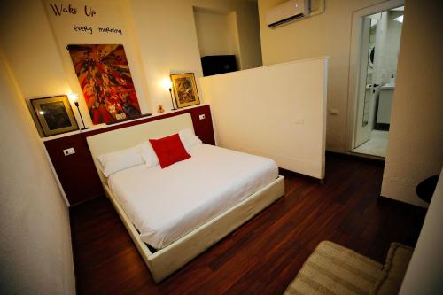 a small bedroom with a white bed with a red pillow at Hosting Dreams Attics - Duomo in Milan