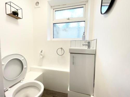 een witte badkamer met een toilet en een raam bij Sandringham House Serviced Rooms in Hartlepool
