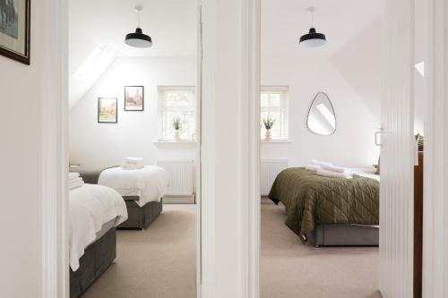a white bedroom with two beds and a mirror at Cosy Cotswolds Getaway - Stow-on-the-Wold - Eagle Cottage in Wyck Rissington
