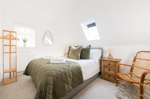 a white bedroom with a bed and a chair at Cosy Cotswolds Getaway - Stow-on-the-Wold - Eagle Cottage in Wyck Rissington