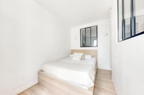 une chambre blanche avec un lit et deux fenêtres dans l'établissement *Le Chic* Proche Paris JO 2024, à Clichy