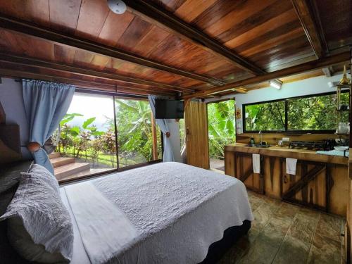 a bedroom with a large bed and a sink at La Fortuna Rainforest Glass Cabin With Suite in Fortuna