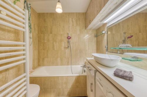 une salle de bain avec une baignoire et un lavabo et une baignoire dans l'établissement Le Jardin du Raincy Paris/Disney JO 2024, à Le Raincy