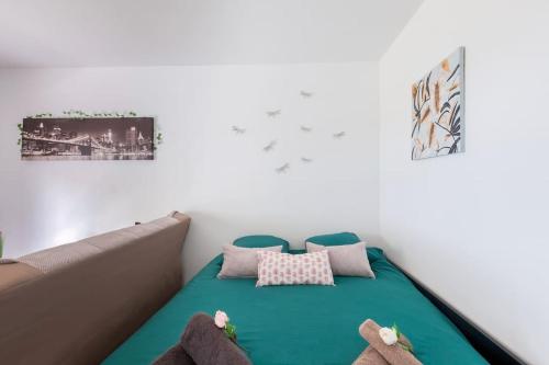 une chambre avec un lit vert avec deux animaux en peluche dans l'établissement Le Jardin du Raincy Paris/Disney JO 2024, à Le Raincy