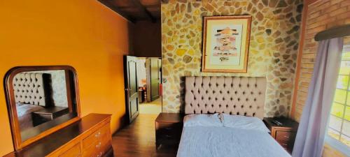 a bedroom with a bed and a dresser and a mirror at Villa Isabella, La Sucursal del Cielo in Siguatepeque