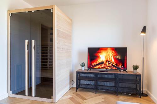 a fireplace in a living room with a tv on a wall at living TIMELESS - Adler Apartments Sasbachwalden in Sasbachwalden