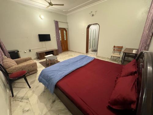 a bedroom with a bed and a couch and a television at Riya Villa - Entire Villa (Kaashi Flora) in Varanasi