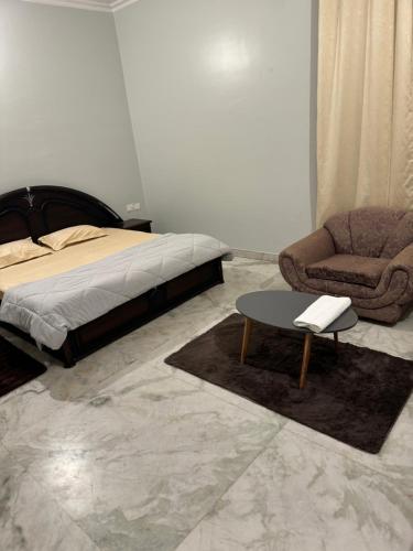a bedroom with a bed and a chair and a table at Riya Villa - Entire Villa (Kaashi Flora) in Varanasi