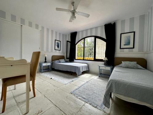 1 dormitorio con 2 camas, escritorio y ventana en Villa in Marbella center, en Marbella