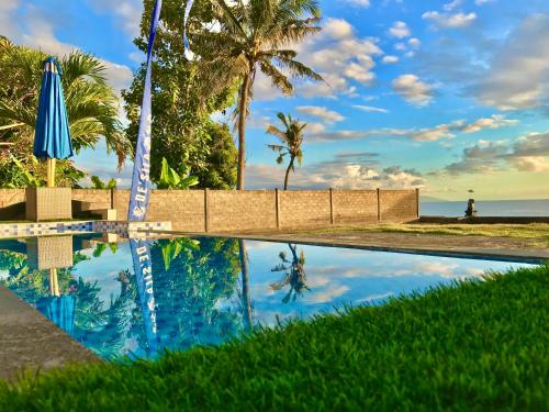 a pool with a reflection of the ocean and palm trees at DESILA Beach House in Nusa Penida