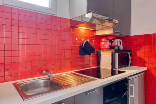 Il comprend une cuisine avec un évier et un mur en carrelage rouge. dans l'établissement *Le Terracota*proche Paris 10min, au Kremlin-Bicêtre