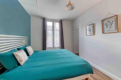 une chambre avec un lit bleu avec une fenêtre dans l'établissement *Le Terracota*proche Paris 10min, au Kremlin-Bicêtre