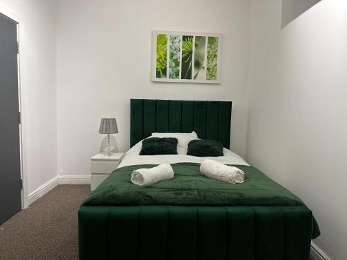 um quarto com uma cama verde e 2 almofadas em 5 Bedroom, 2 bath Leeds Hideaway Haven em Headingley