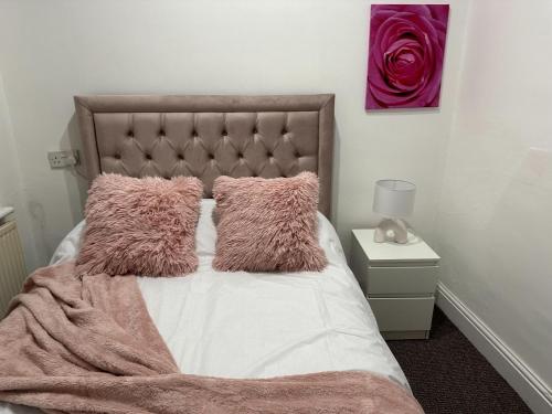 uma cama com almofadas cor-de-rosa e um cobertor cor-de-rosa em 5 Bedroom, 2 bath Leeds Hideaway Haven em Headingley