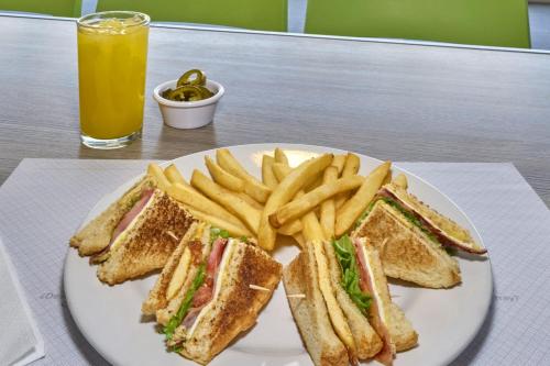 a plate with a sandwich and french fries and a glass of orange juice at City Express by Marriott Ciudad de Mexico Aeropuerto in Mexico City