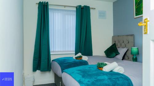 two beds in a bedroom with green curtains at 2ndHomeStays-Dudley-Sleeps 12 in Dudley