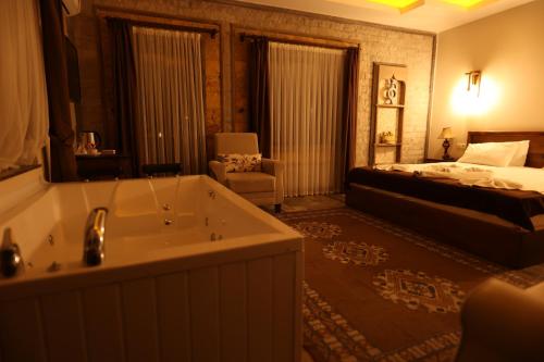 a bathroom with a tub and a bedroom with a bed at EL NAZAR STONE SUİTE in Uchisar