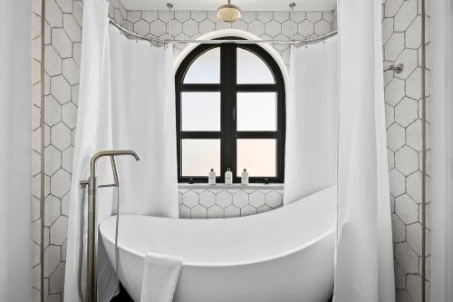a white bathroom with a tub and a window at Las Luces in Spicewood
