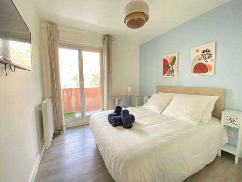 een slaapkamer met een wit bed met een teddybeer erop bij Le Cocon Urbain - Agréable & Chic in Courcouronnes