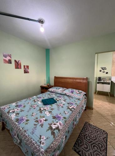 a bedroom with a bed with a floral bedspread at Hospedagem Zefino in Cunha