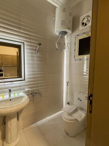 ein Badezimmer mit einem Waschbecken, einem WC und einem Spiegel in der Unterkunft فندق تلاقِ in Medina