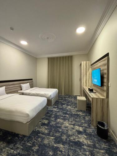 ein Hotelzimmer mit 2 Betten und einem Flachbild-TV in der Unterkunft فندق تلاقِ in Medina