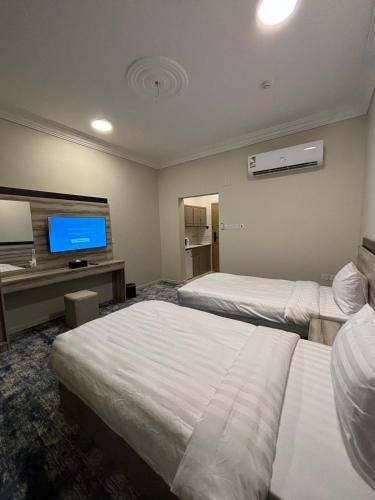a hotel room with two beds and a flat screen tv at فندق تلاقِ in Al Madinah