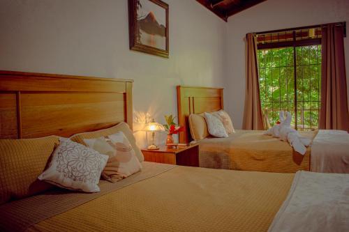 a bedroom with two beds and a window at Arenal Descanso in Fortuna