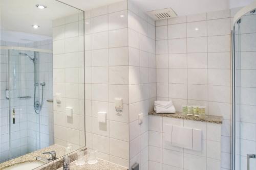 een witte badkamer met een douche en een wastafel bij Courtyard by Marriott Dresden in Dresden