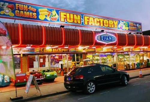 a black car parked in front of a fun factory at Caravan holiday let 2 bedroom happy days SOUTH chapel saint Leonards 05 in Chapel Saint Leonards