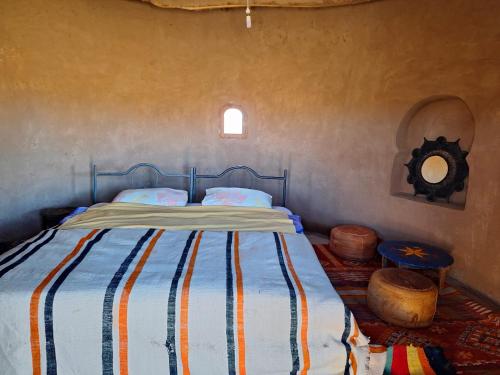 una camera da letto con un letto con una coperta a righe di M'hamid Desert Camp Tours a M'Hamid