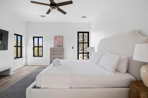 a white bedroom with a white couch and a ceiling fan at Las Luces in Spicewood