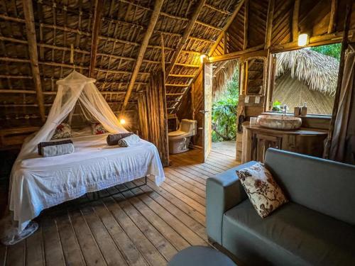 a bedroom with a bed and a couch in a room at Bungalows India & boutique, El Valle, Samana in Santa Bárbara de Samaná