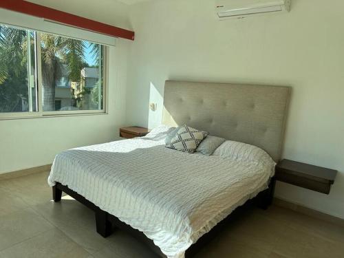 1 cama en un dormitorio con ventana grande en Casa hermosa y acogedora en condominio privado, en Puerto Vallarta