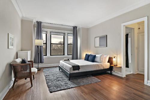 a bedroom with a bed and a chair and windows at Enchanting 1BR Urban Retreat in Hyde Park - Windermere 401 in Chicago