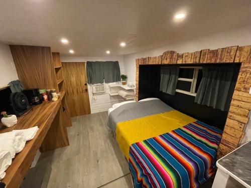 1 dormitorio con 1 cama con una manta a rayas de colores en Camper with A/C - Glamping 3 Idiomas, en El Sargento