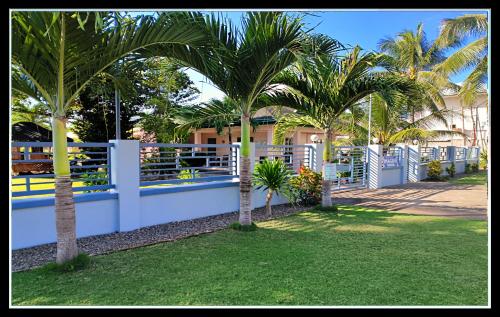 a white fence with palm trees in a yard at Imagine Bohol in Panglao